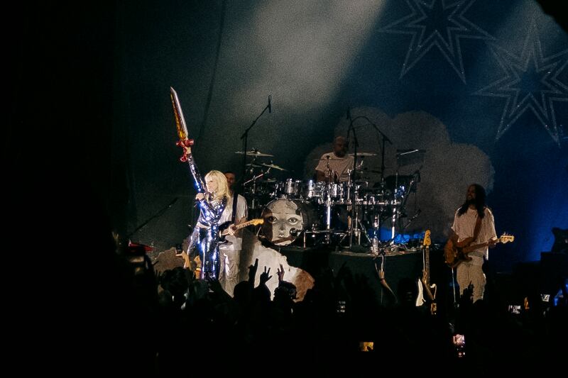 A photo of Carly Rae Jepsen holding a sword up on stage.