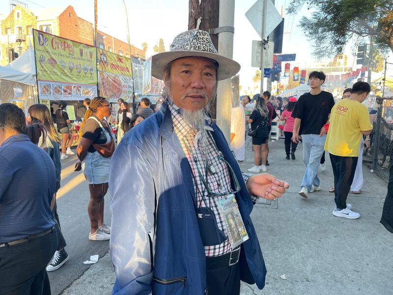 Photo of a man with a fedora covered in writing wearing a plaid shirt and a blue jacket
