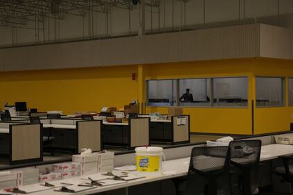 A person stands in the yellow ‘command center’ of the facility where operations throughout the ballot processing center are organized.