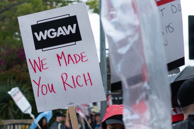 Intermittent rain causes words drawn by markers to bleed down the signs while some protesters cover their signs with plastic bags.