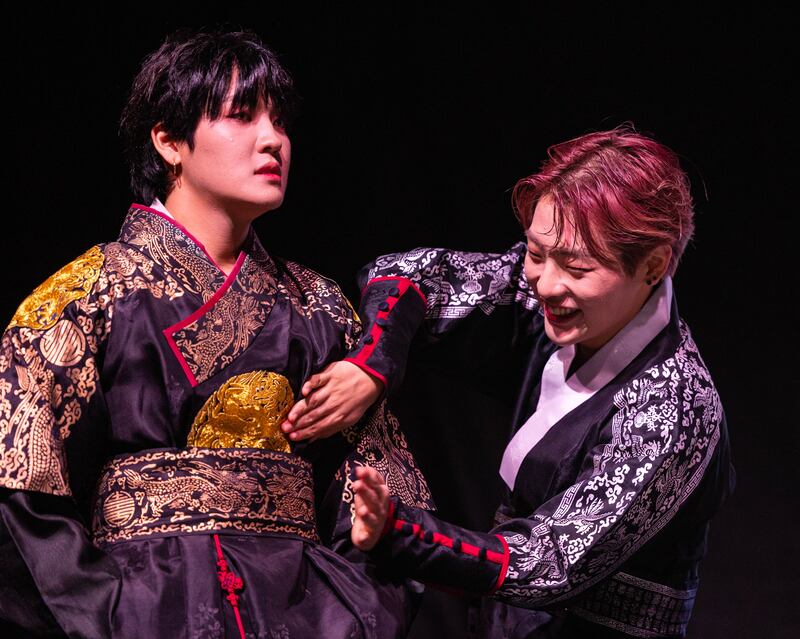 KINGDOM member Mujin builds anticipation for the announcement of the winner by drumming on fellow band member, Louis.