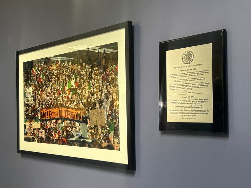 A framed photograph and a silver plaque hang on a blue wall.