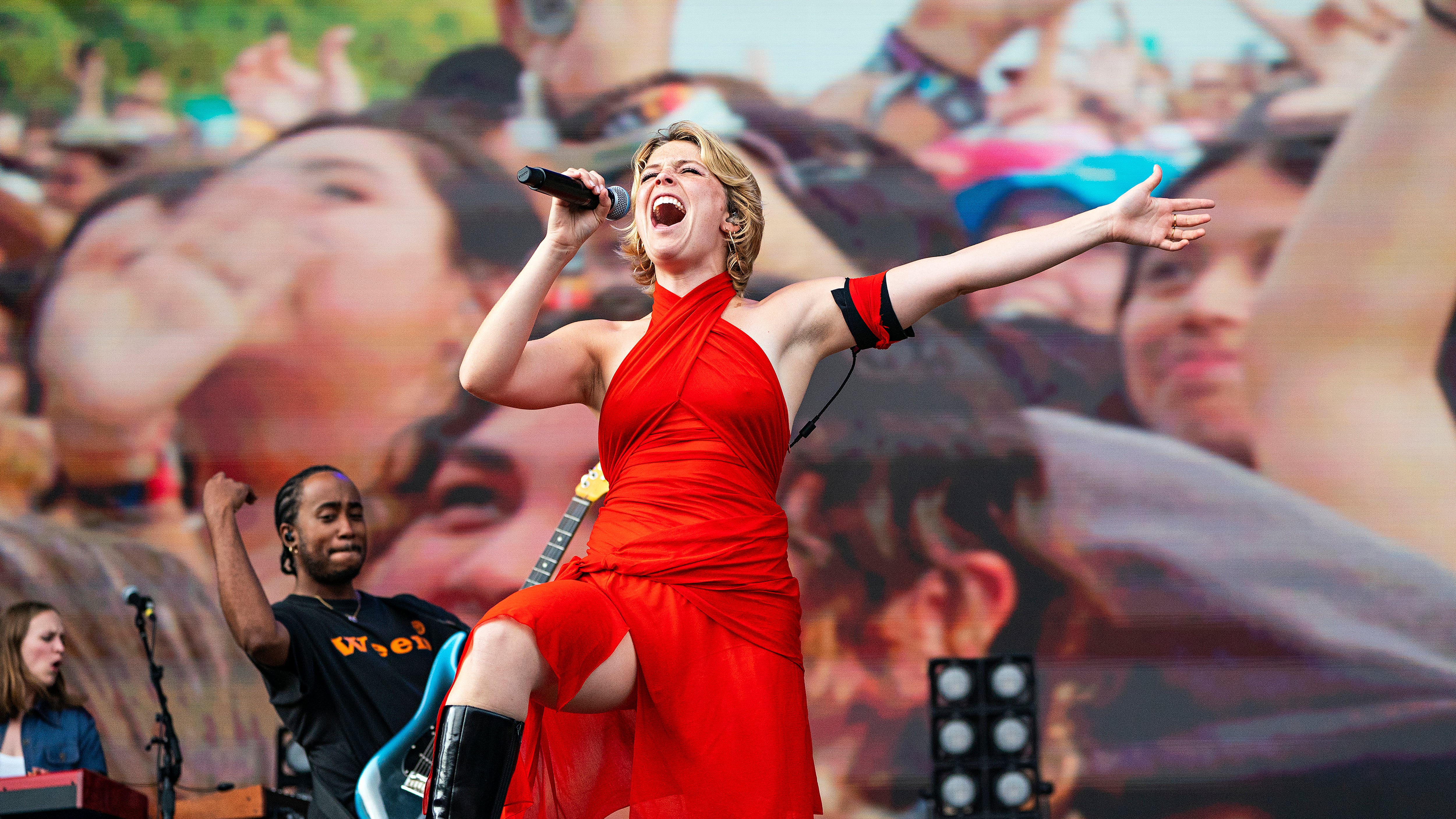 A photo of Maggie Rogers in a red dress performing on stage.