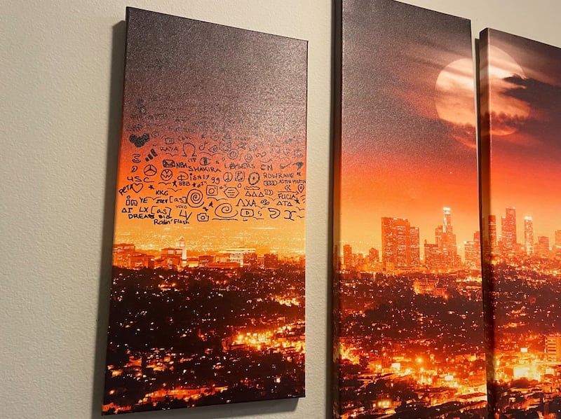 Against an orange-lit canvas of the Los Angeles skyline, different brand logos are scribbled in sharpie.