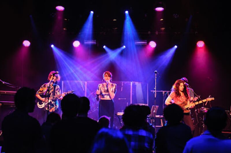 MUNA performs onstage under purple and pink lights.