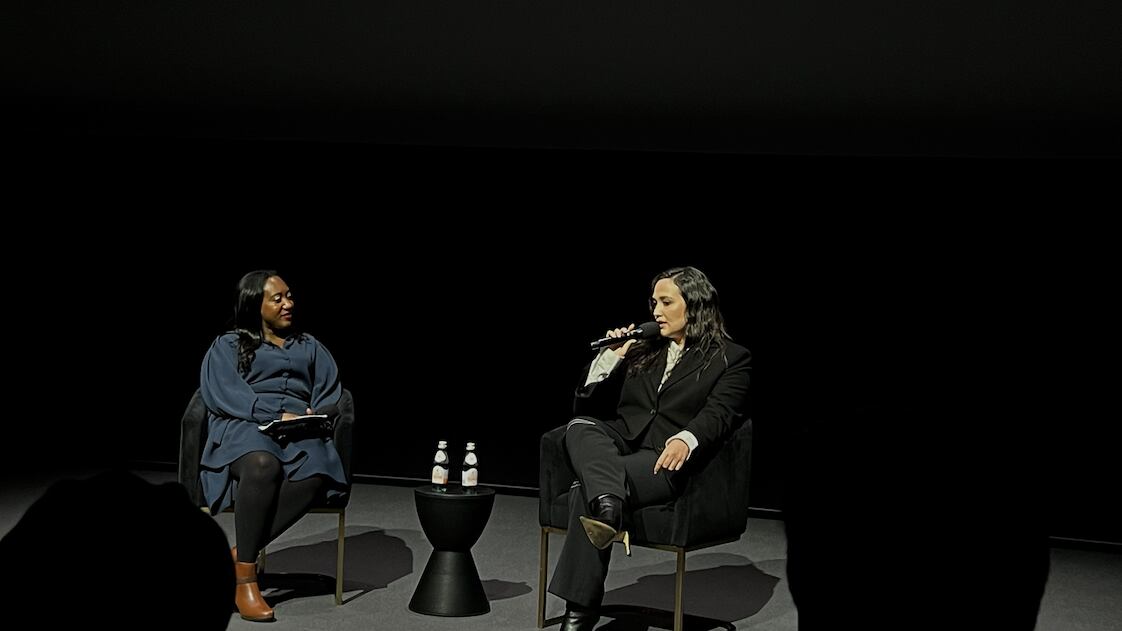 Gladstone and Jackson sit on a stage with a black background behind them.