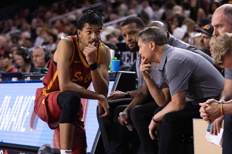 Chad Baker-Mazara kneels on the sideline and talks to head coach Eric Musselman.