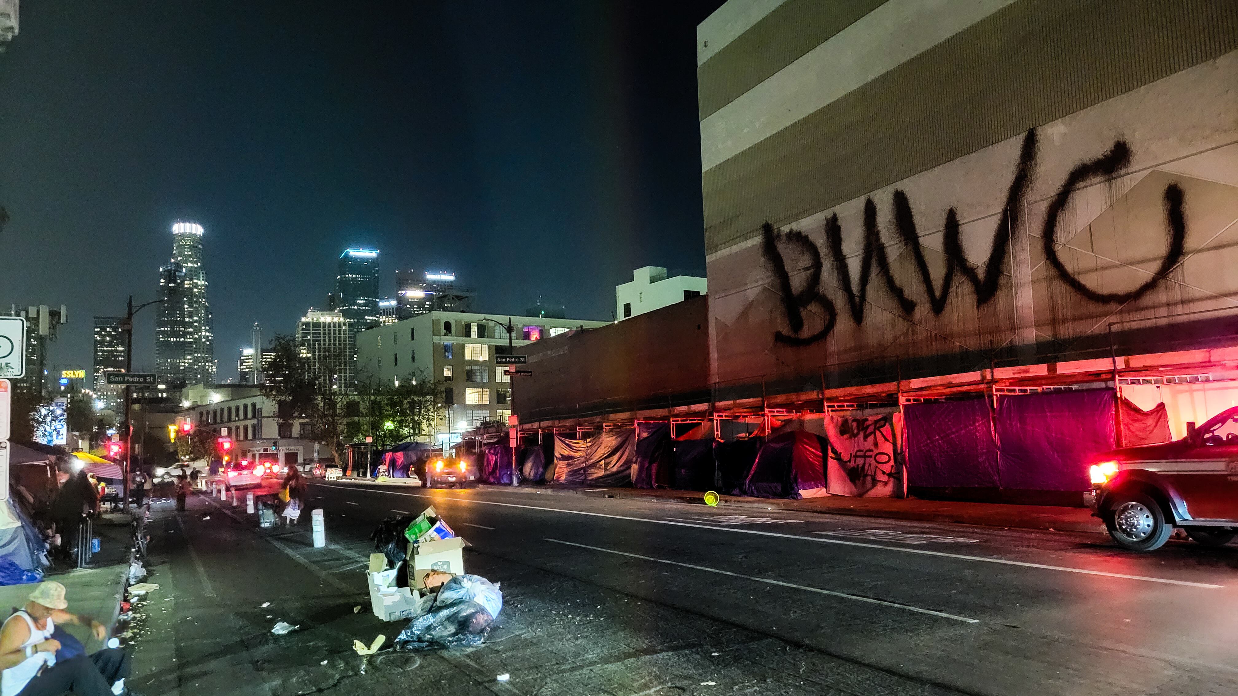 A photo of Skid Row at night. Tents line the sidewalk.