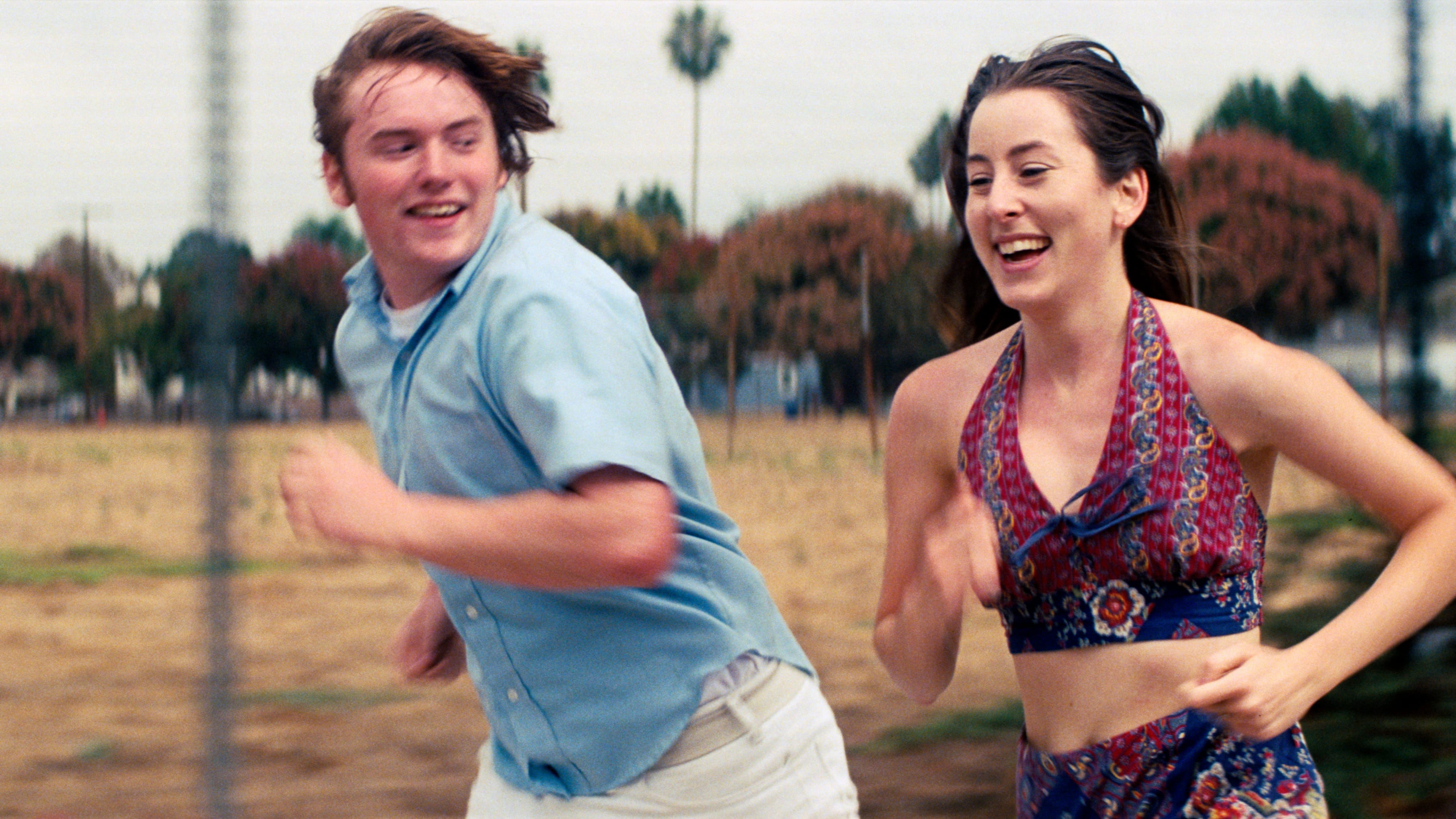 Photo of Alana Haim and Cooper Hoffman running in the movie 'Licorice Pizza.'