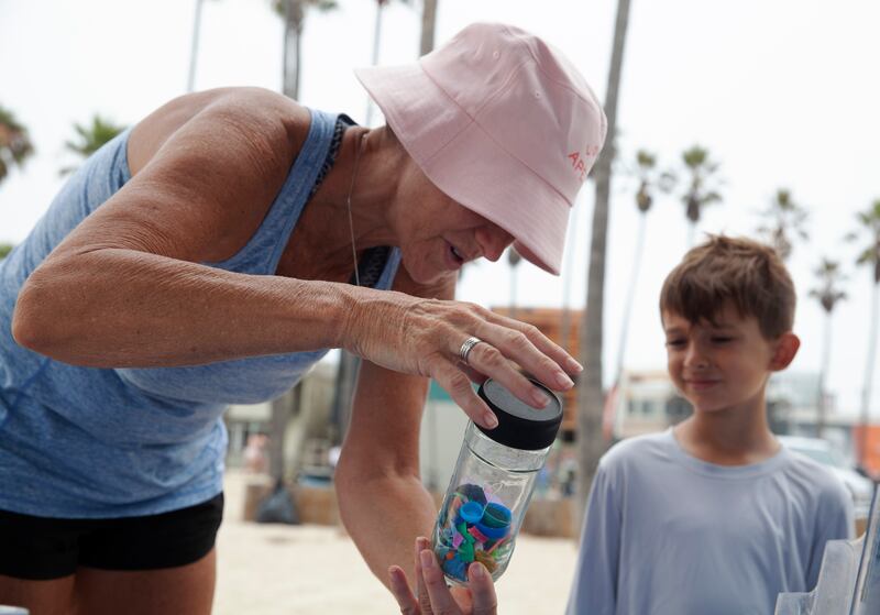 A woman shows her grandson some plastic waste in a bottle.