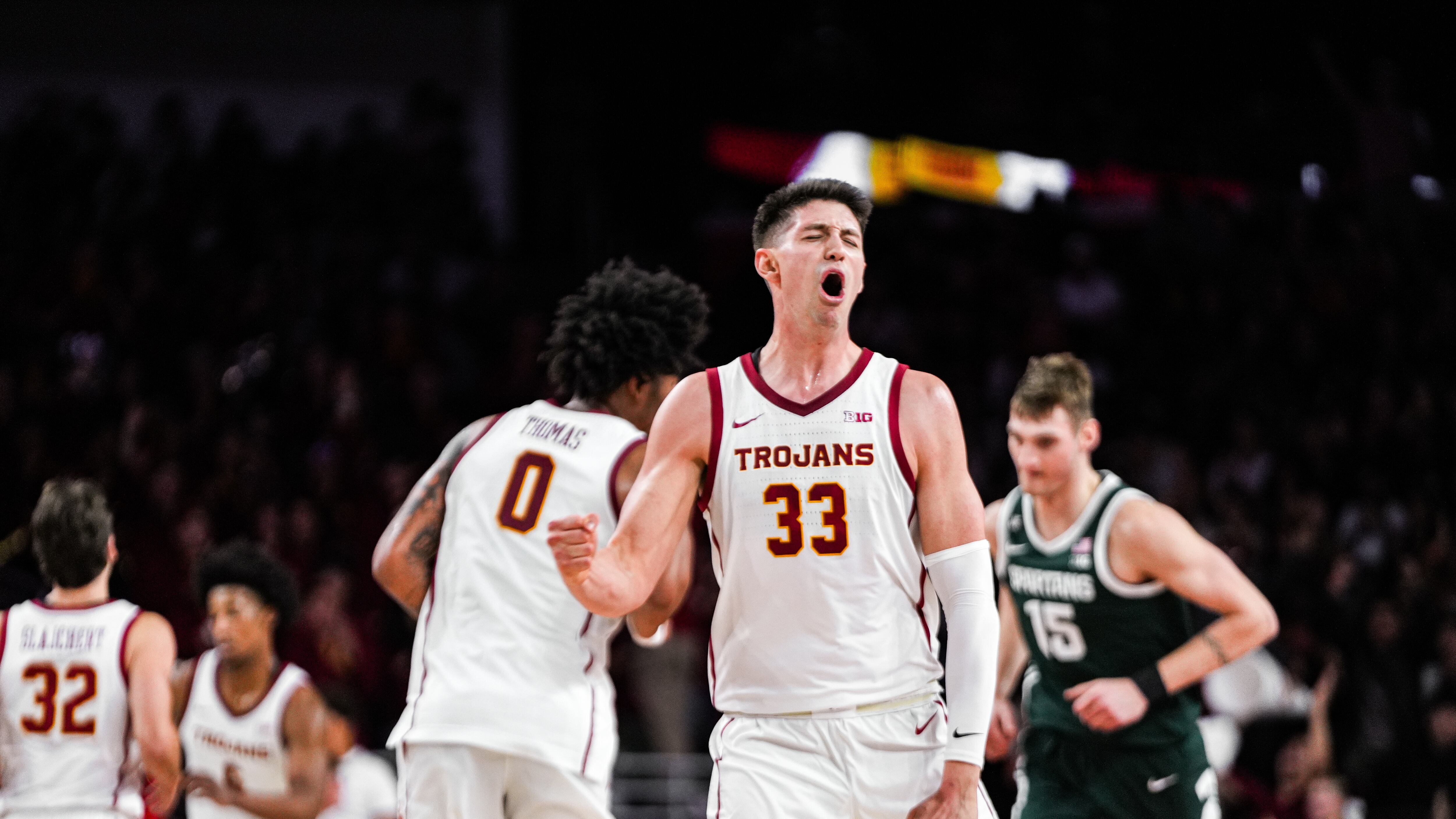 Four USC men's basketball players wearing white jerseys during game versus Michigan State.