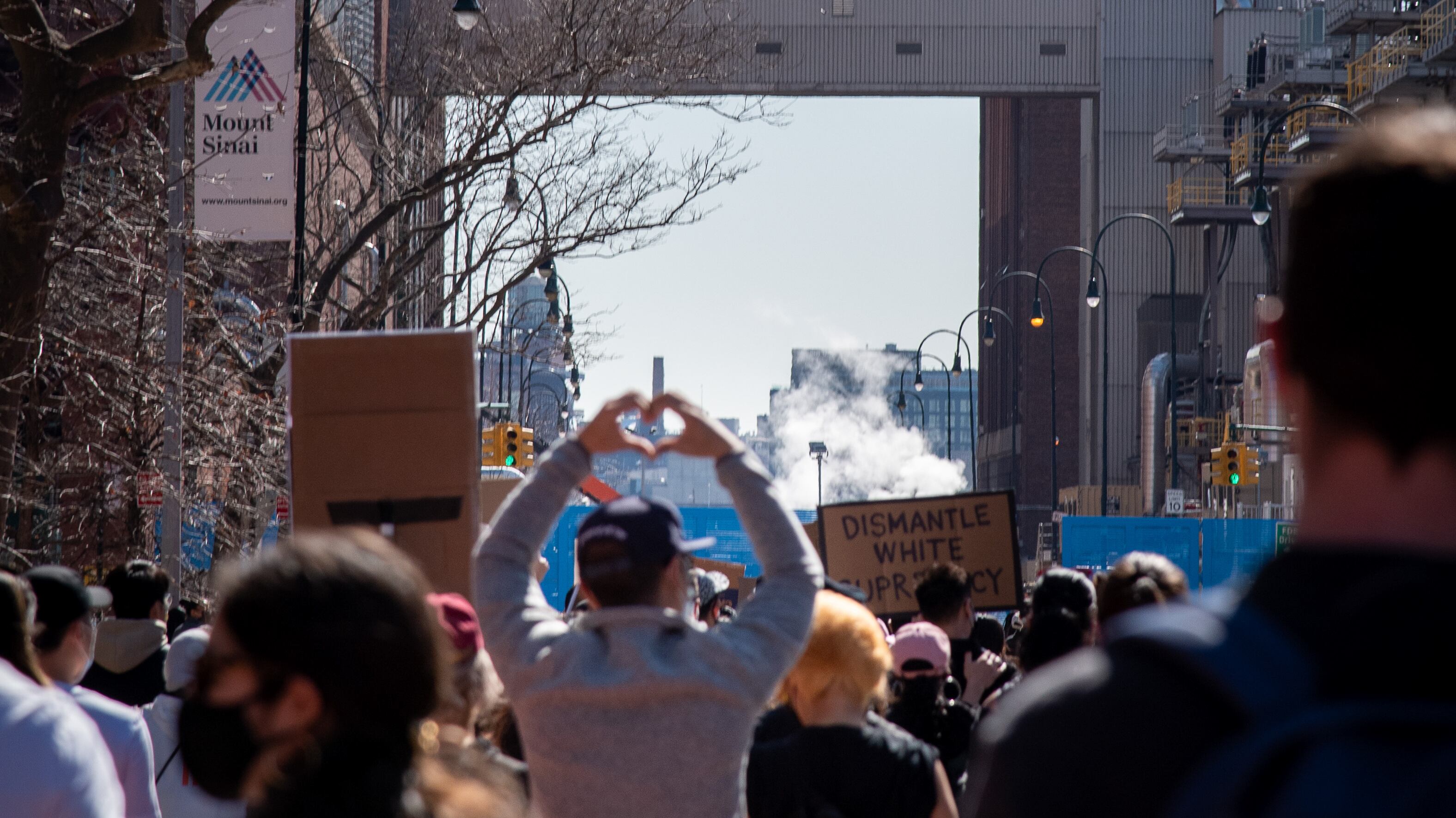 A photo of a protester holding their hands into a heart