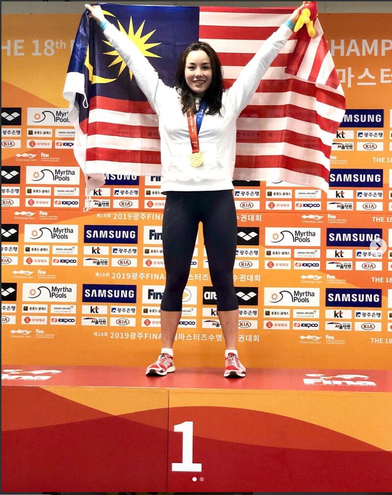 Cindy Ong standing on a podium in the FINA Masters 2019 with the Malaysian flag.