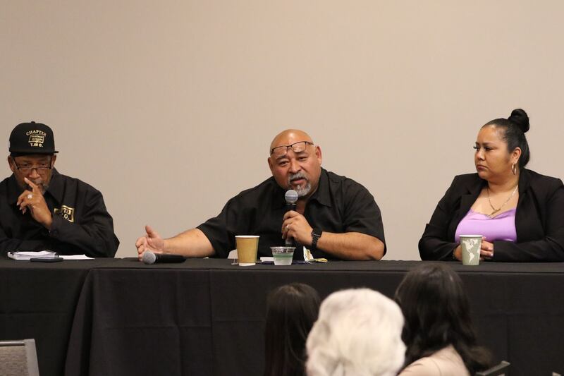 Photo of three people sittting at a table speaking.