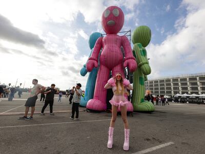 A photo of a fan wearing an all pink outfit and posing in front of inflatable alien figures.