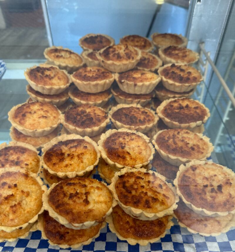 Photo of coconut tarts in a glass case on a blue checkered paper.