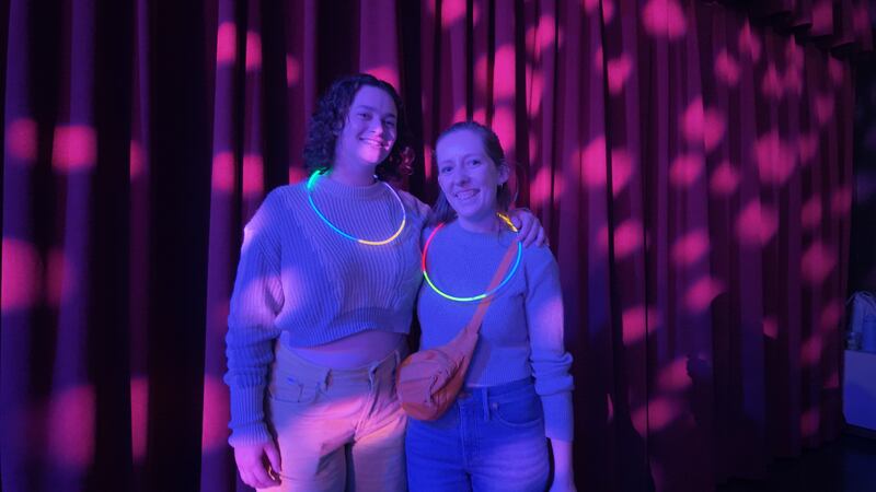 A photo of two women with a ring of glowsticks around their neck