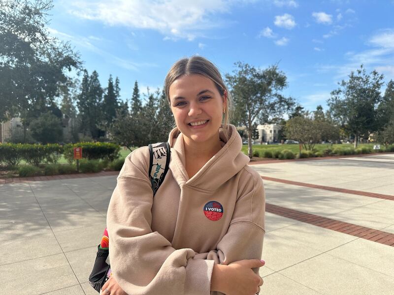 Williams in front of a lawn, wearing an "I Voted" sticker.