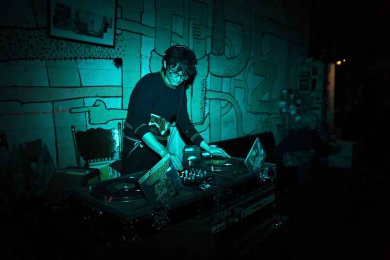 A photo of a DJ at a booth with blue lighting surrounding him.