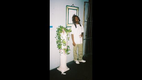 Photo of the rapper Mavi next to a potted plant.