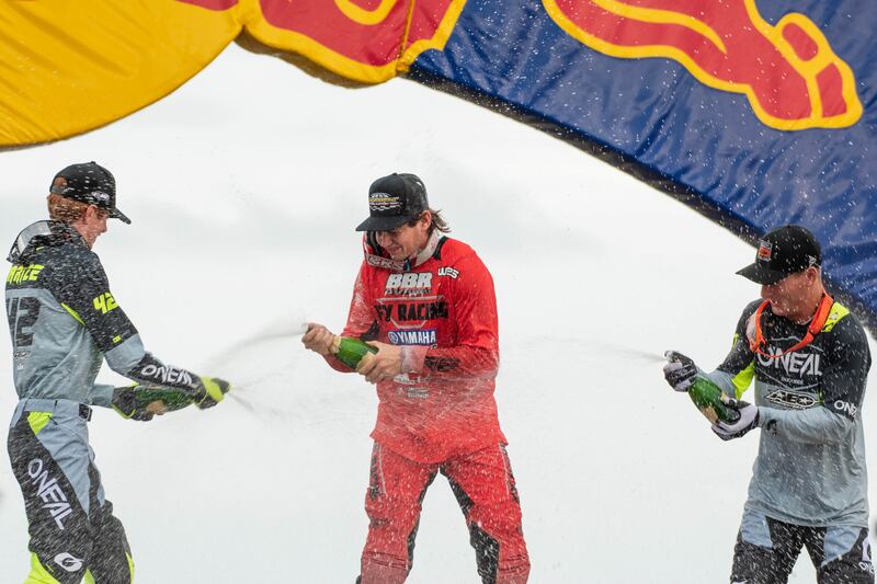 Carson Brown (center), Josh Varize (left) and Derek Kelley (right) celebrate their victories with champagne at the end of the Straight Rhythm 125cc race. Brown earned first place, Varize second and Kelley third.