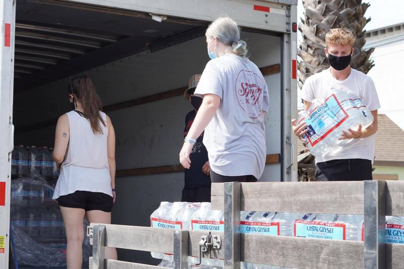 Volunteers unloading water bottle cases from the U-Haul - the process of unloading from U-Haul and loading cars