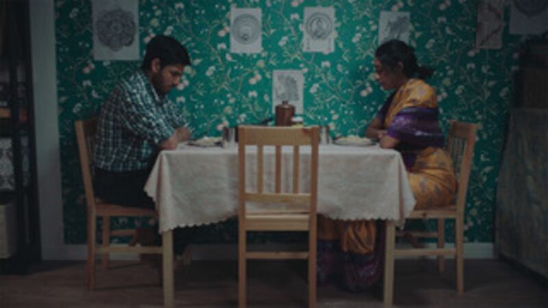 Film still of two people sitting at a table facing each other