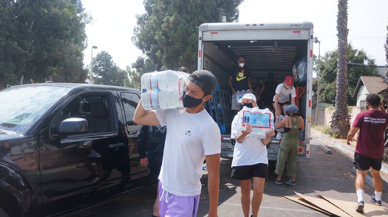 volunteers carrying water from u-haul to cars - the process of unloading from U-Haul and loading cars