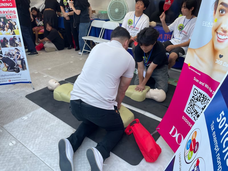 Photo of two people on their knees with their hands on the chest of a mannequin