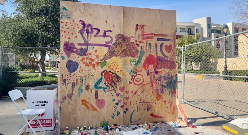 A wooden board is filled with paintings from children in many different colors