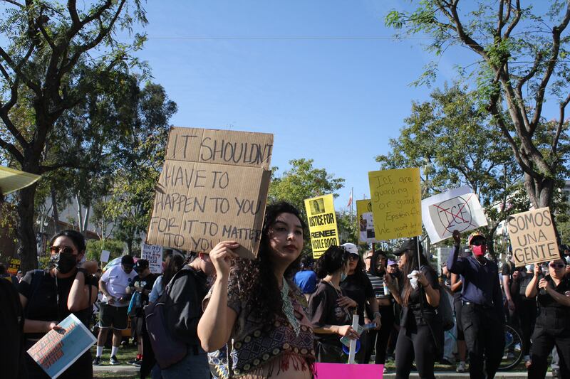 A woman stands in Gloria Molina Grand Park surrounded by fellow protesters.
