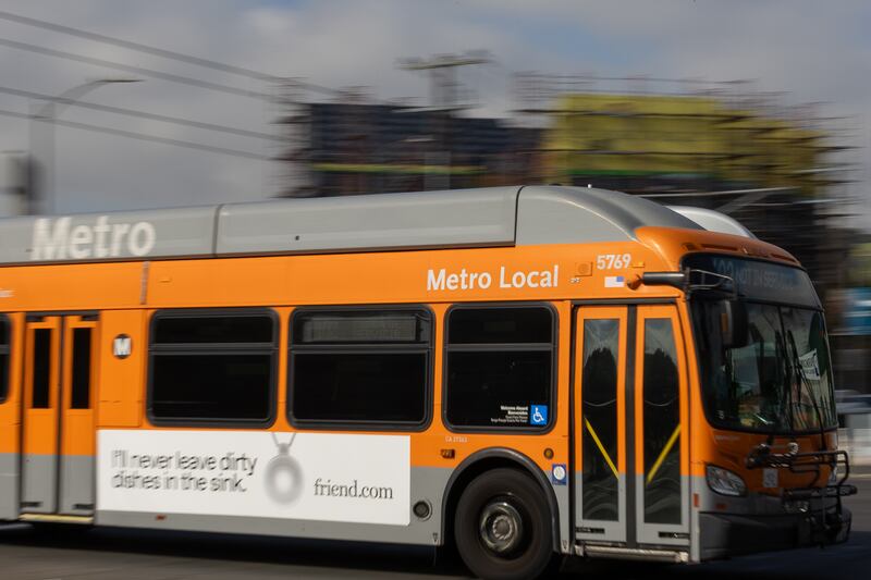 An orange bus drives down the street.