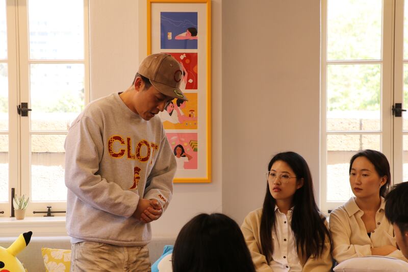 Photo of a man in a hat speaking to a group of students