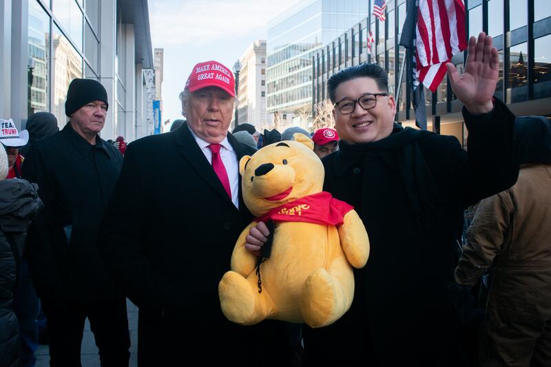 A picture of a Donald Trump impersonator and Kim Jong Un impersonator holding a Winnie-the-Pooh stuffed animal.