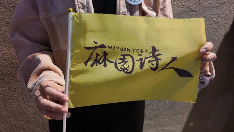 Photo of a person holding a small yellow flag with a logo
