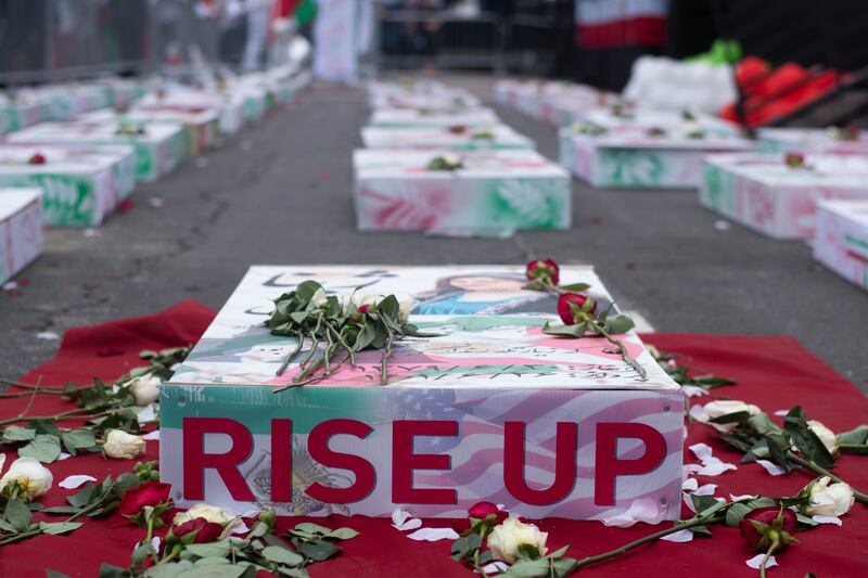 Boxes with people sit in front of the stage, a symbol of all the killed youth in the Women Life Freedom movement.