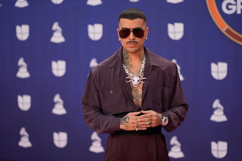 Photo of a man in a dark purple suit against a light purple background.