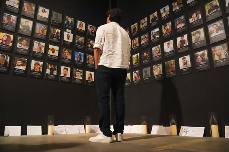 USC student looking at pictures of Israelis killed at the Nova Music Festival Exhibit in Los Angeles.
