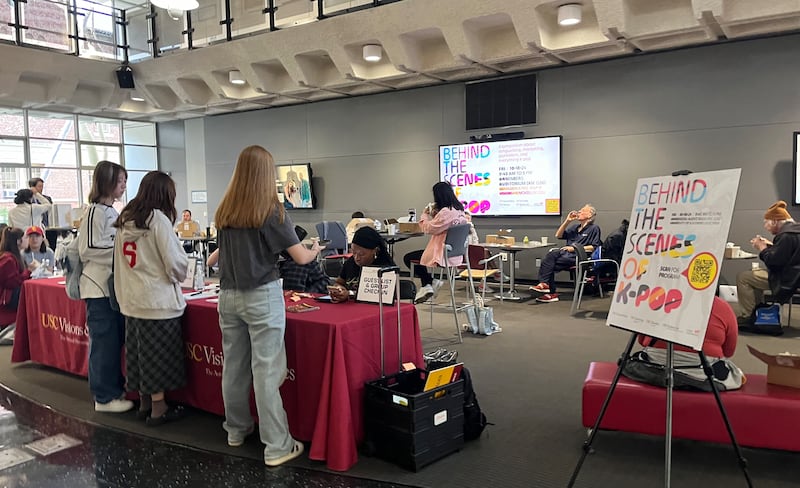 Photo of a crowded lobby with people talking in front of a desk