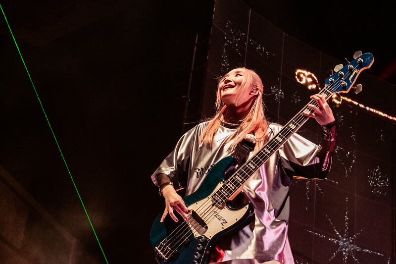 Photo of a woman with pink hair playing a large bass guitar
