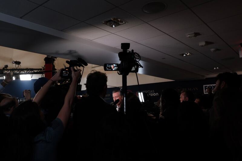 Governor Gavin Newsom answers questions while surrounded by the press.