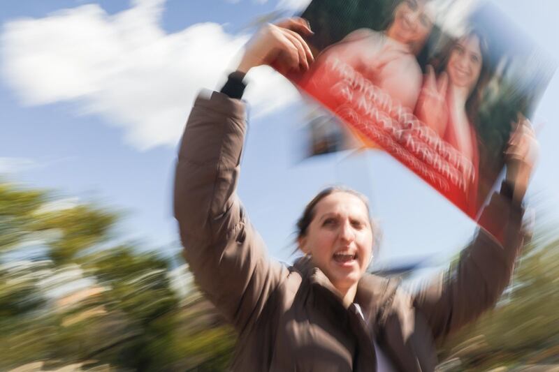 Hannah Woodworth, blurry, holidng a campaign sign and shouting.