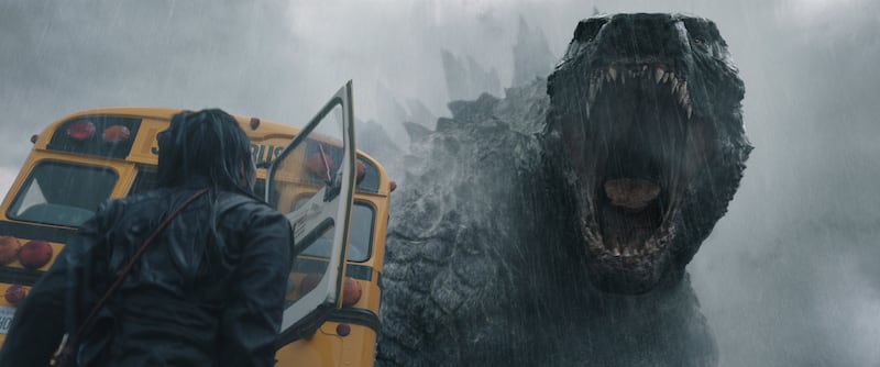 Screenshot of a woman next to a falling bus in front of a large lizard