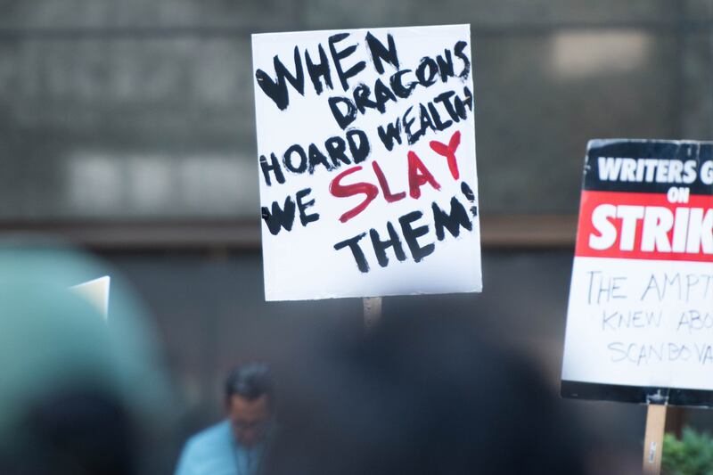 A sign with "When Dragons Hoard Wealth We Slay Them!" written on it.
