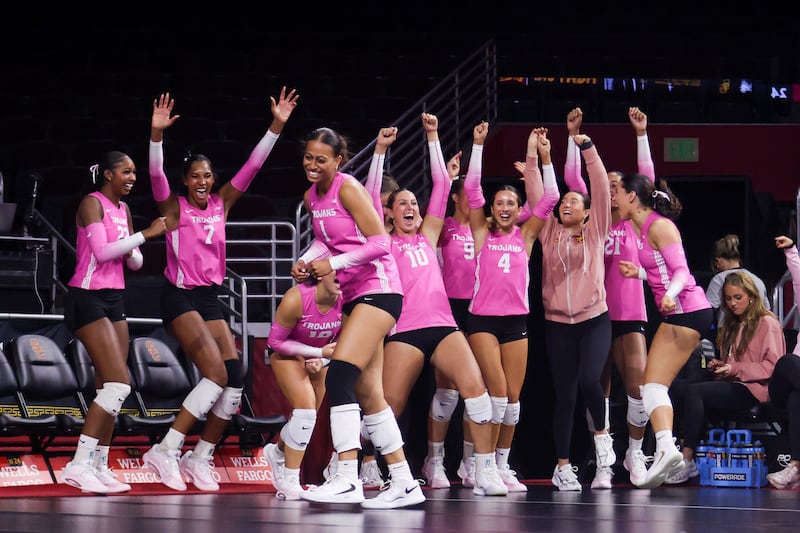 Faumuina and teammates celebrate from the sidelines with smiles and arms raised.