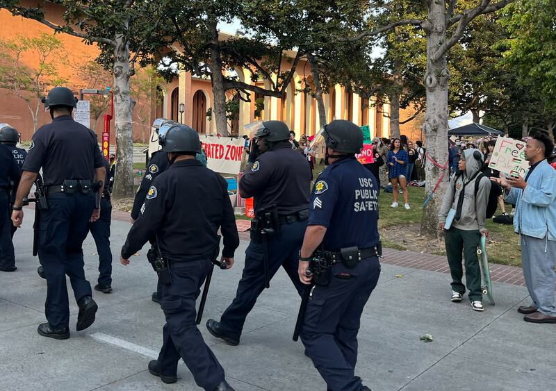 DPS officers in blue uniforms and helmets march outside.