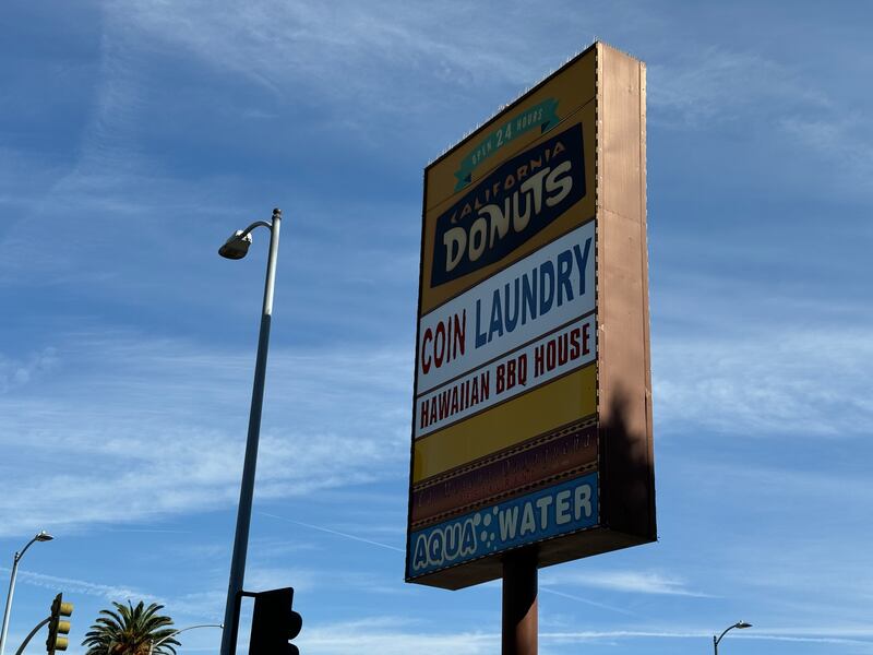 Photo of a large sign reading "California Donuts," "Coin Laundry," and "Hawaiian BBQ House"