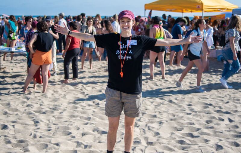 Girl stands on beach with her arms out.