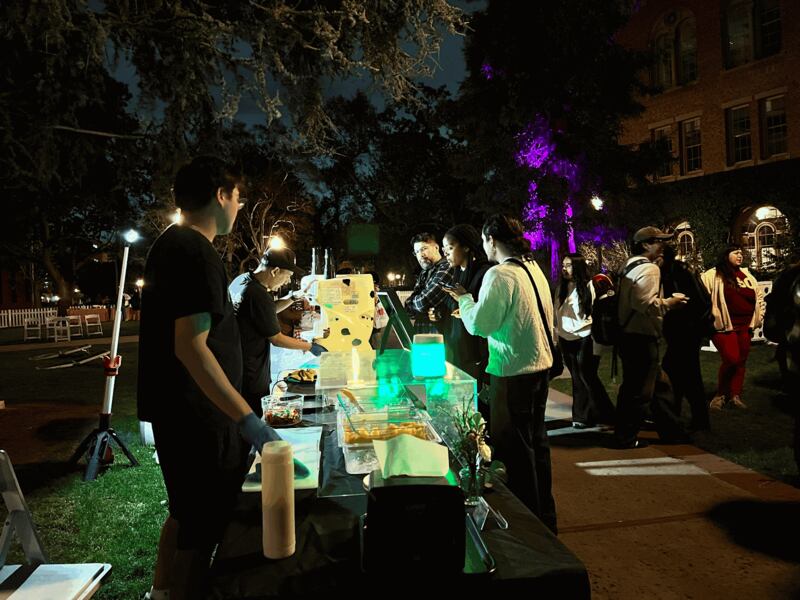 Photo of people at a table grabbing food.