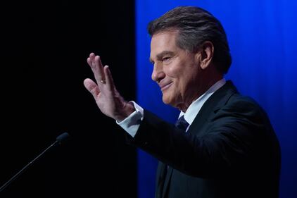 Photo of a Steve Gardy holding out his hand at the podium